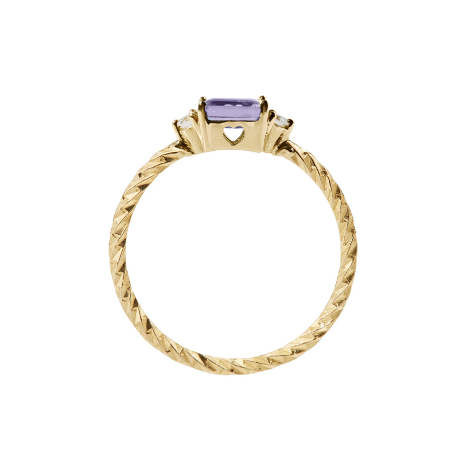 Amethyst trilogy birthstone ring with two white diamond side stones on a textured gold band. Sideview showing a heart cut out on the stone setting.