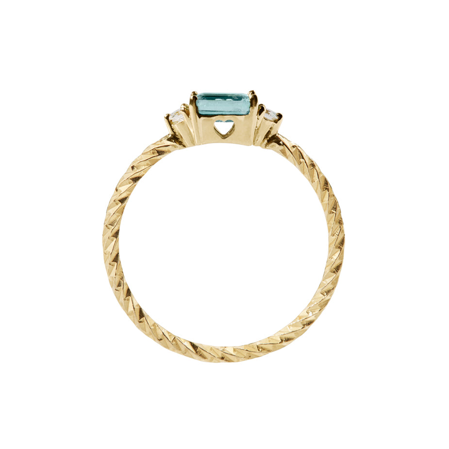 Aquamarine trilogy birthstone ring with two white diamond side stones on a textured gold band. Sideview showing a heart cut out on the stone setting.