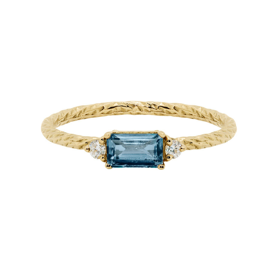 Blue sapphire trilogy birthstone ring with two white diamond side stones on a textured gold band.