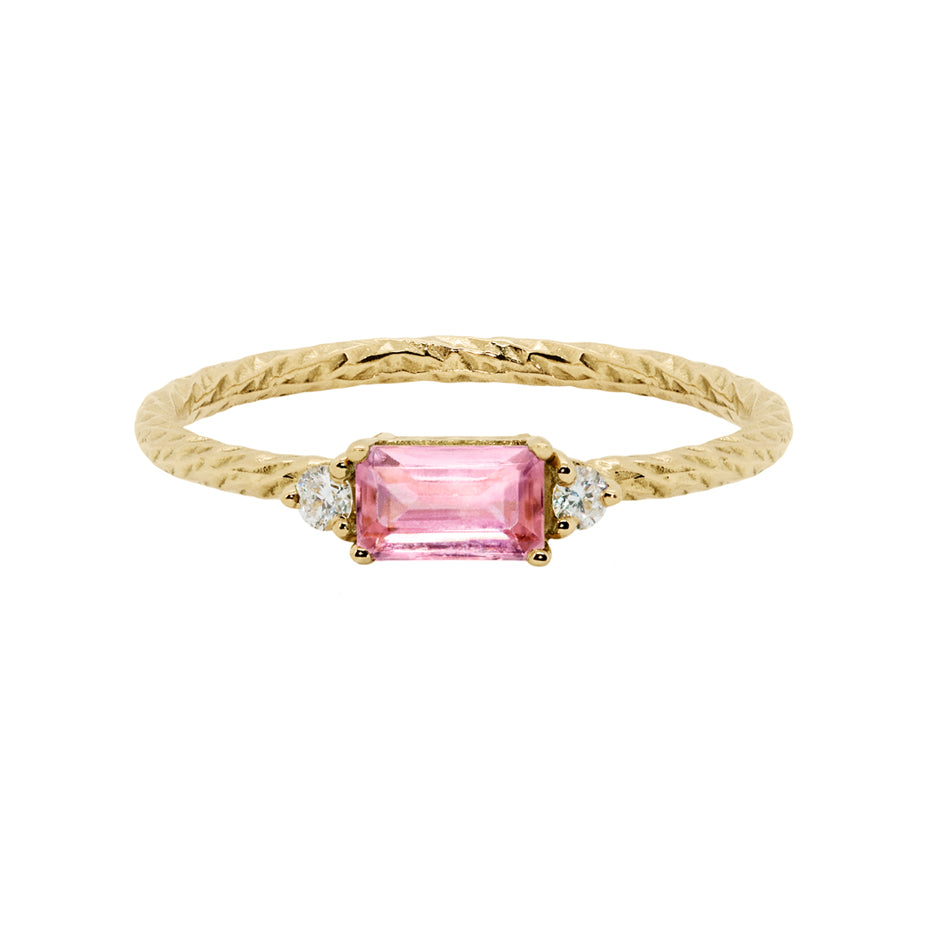 Pink tourmaline trilogy birthstone ring with two white diamond side stones on a textured gold band.