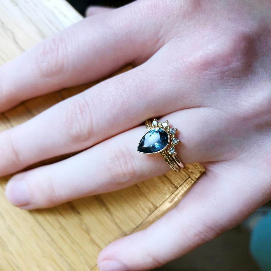 Wearing the pear shaped Harmony engagement ring with a blue grey sapphire, combined with the Titania tiara wedding band with salt & pepper diamonds.