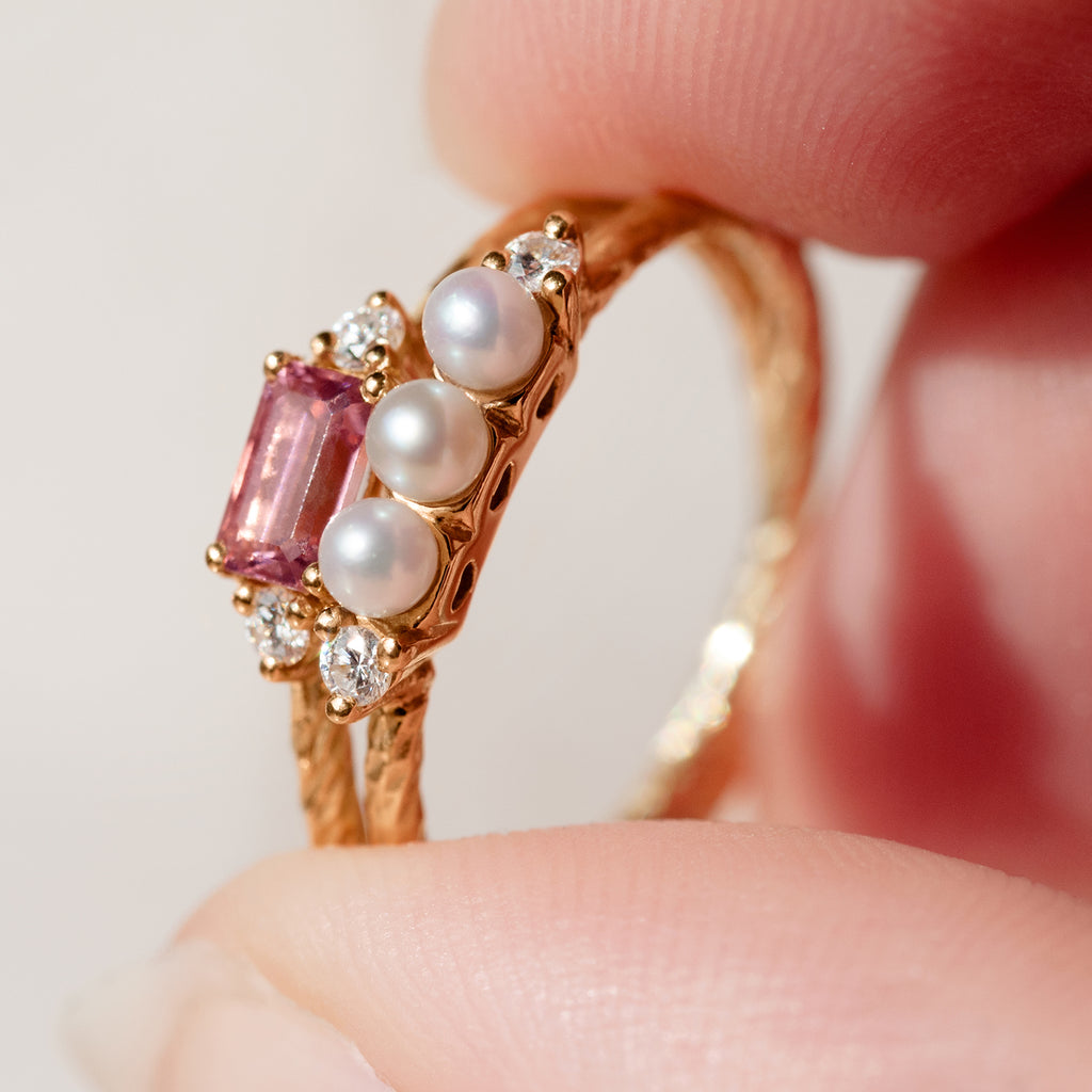 A close-up of the pearl and pink tourmaline birthstone rings stacked together.