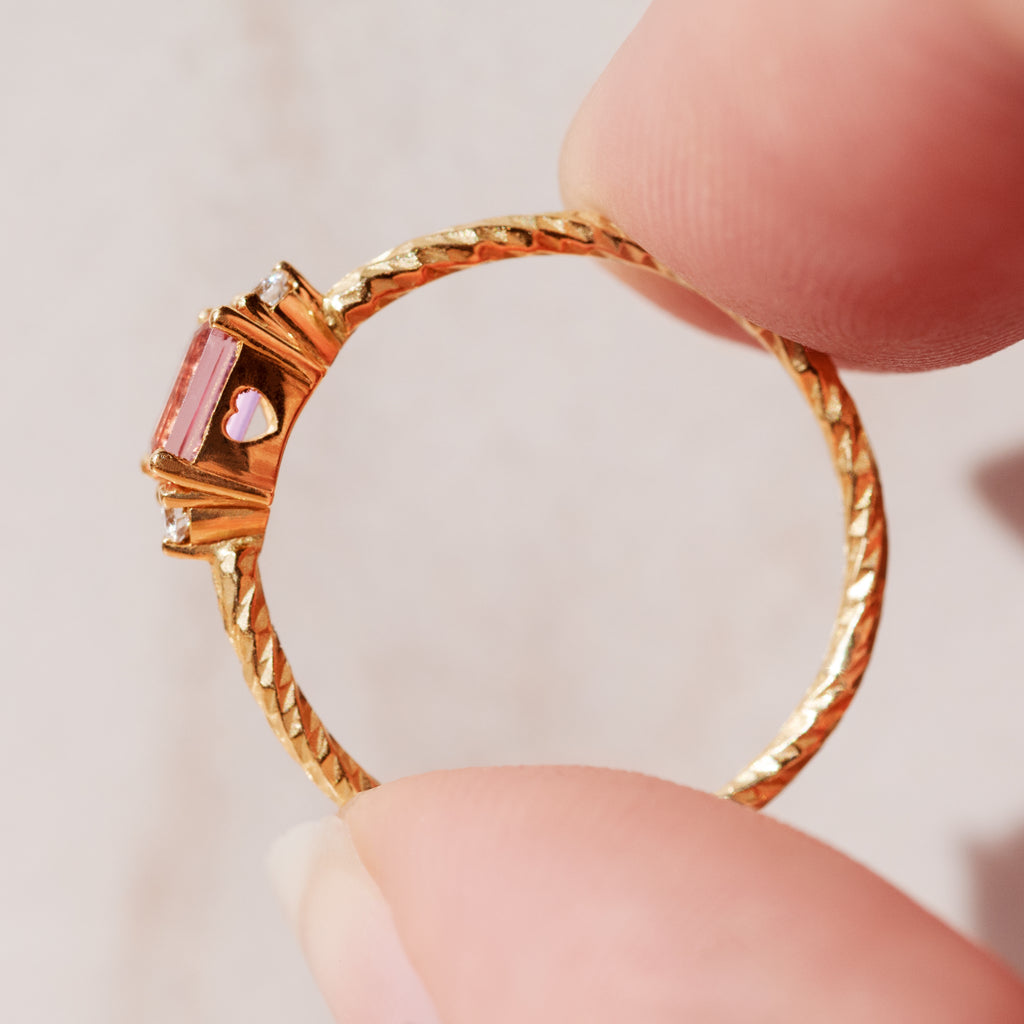 A sideview of the pink tourmaline birthstone ring showing the heart cut out on the stone setting.