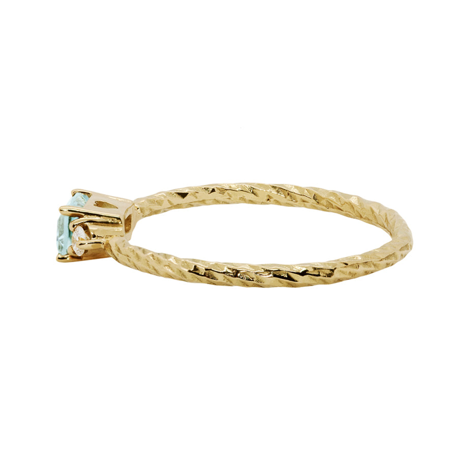 Aquamarine trilogy birthstone ring with two white diamond side stones on a textured gold band.