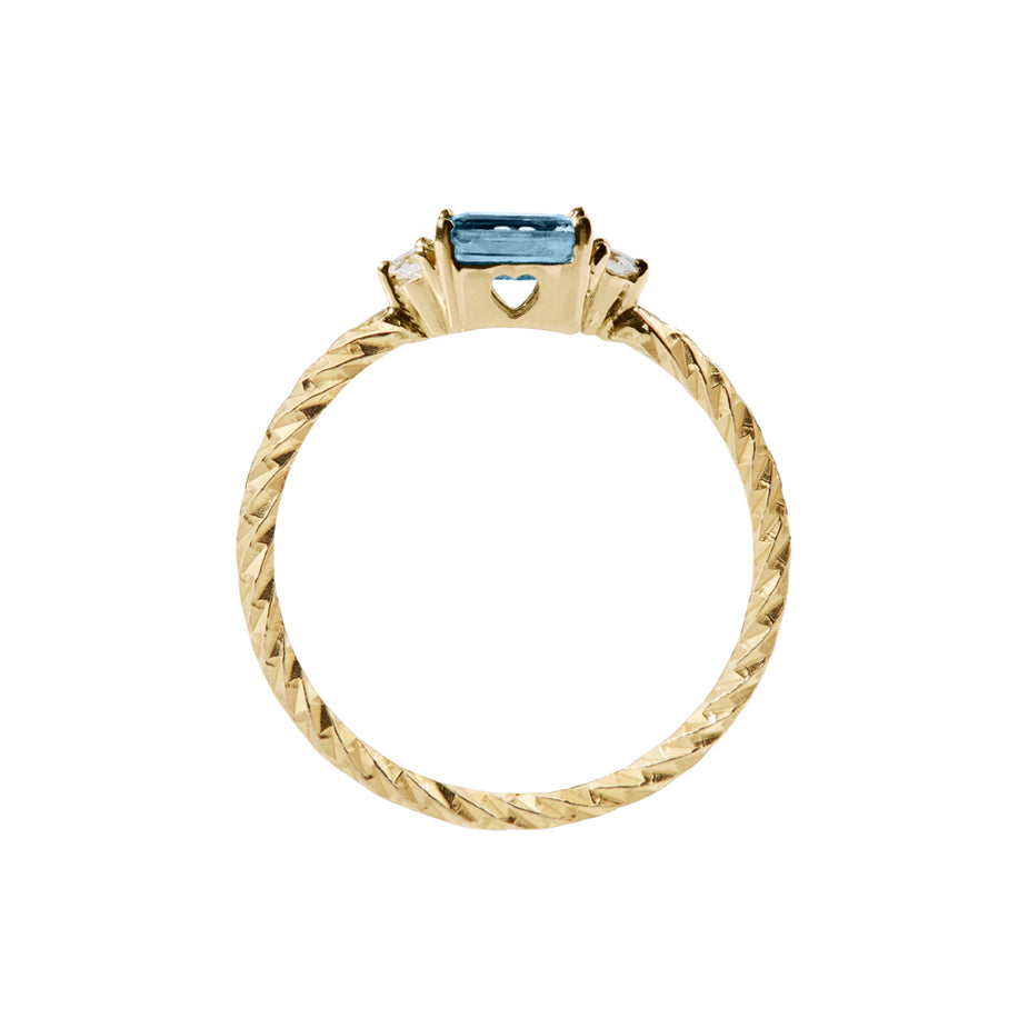 Blue sapphire trilogy birthstone ring with two white diamond side stones on a textured gold band. Sideview showing a cut out heart on the stone setting.