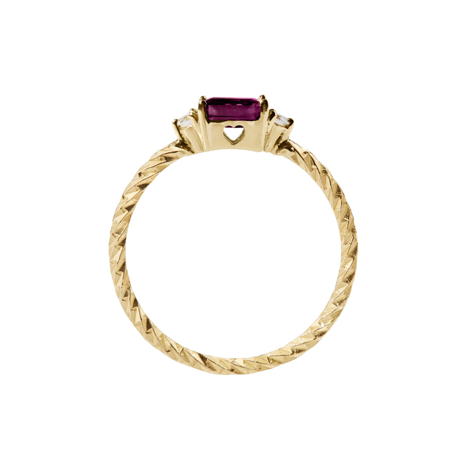 Ruby trilogy birthstone ring with two white diamond side stones on a textured gold band. Sideview showing a cut out heart on the stone setting.