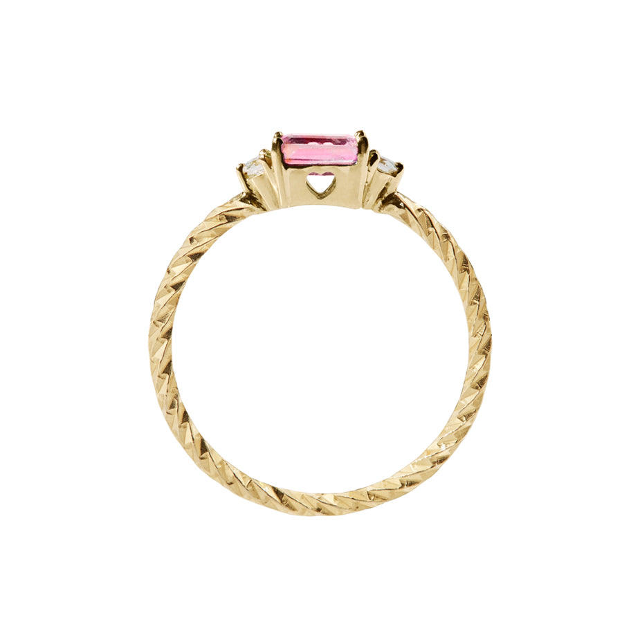 Pink tourmaline trilogy birthstone ring with two white diamond side stones on a textured gold band. Sideview showing a cut out heart on the stone setting.