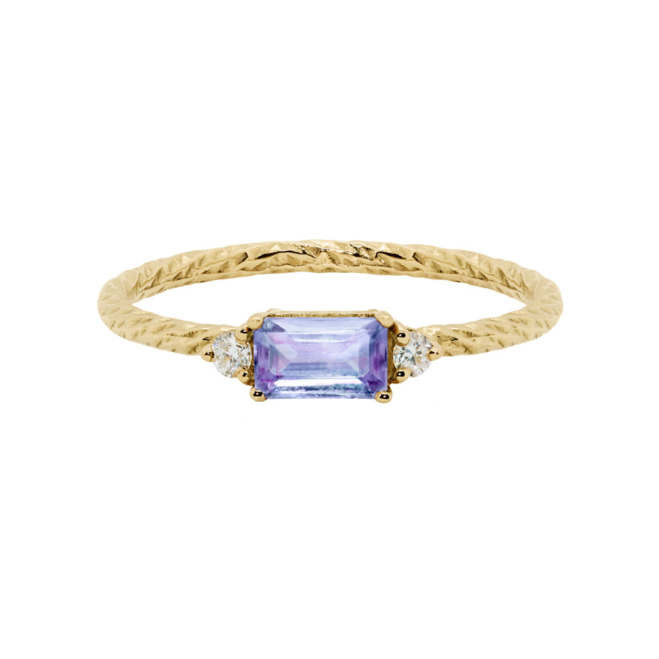 The tanzanite trilogy birthstone ring with two white diamonds on either side and a textured band.