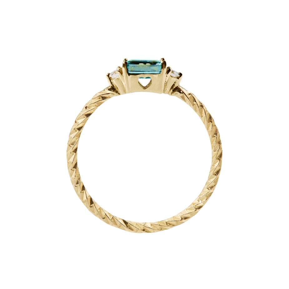 London blue topaz trilogy birthstone ring with two white diamond side stones on a textured gold band. Sideview showing a cut out heart on the stone setting.